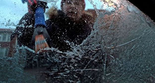 Photo of man scraping ice from car windshield